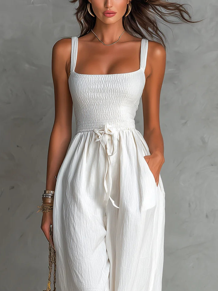 White sleeveless jumpsuit with a square neck, pleats, adjustable drawstring, and wide leg